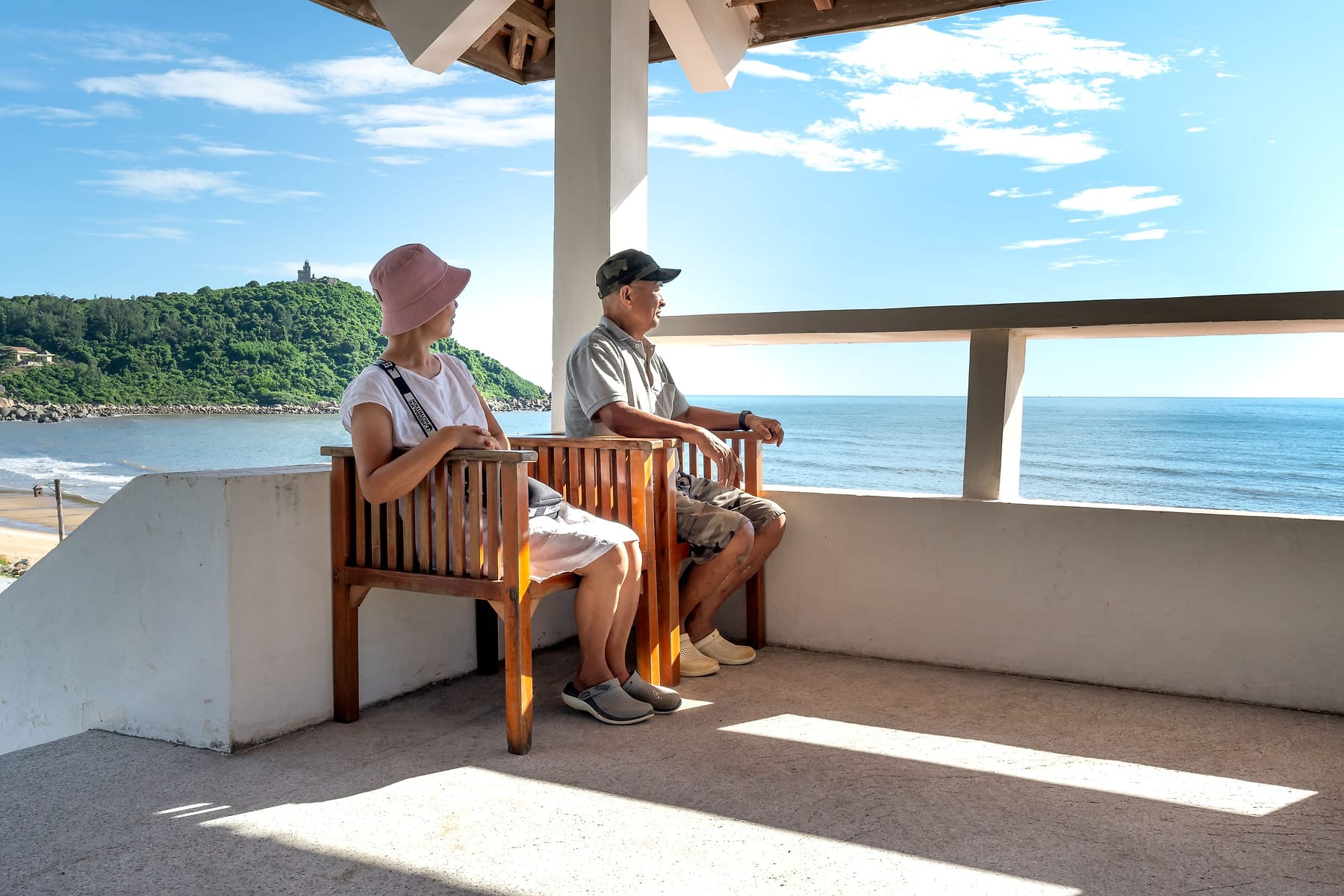 A senior couple sitting together on an ocean-view balcony